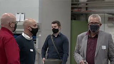 Vier Personen mit Maske stehen in einem mittelständischen Betrieb