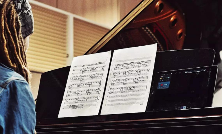 Musikerin am Klavier mit Smartphone und Noten