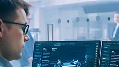 Ein Mann vor 2 PC-Monitoren mit digitalen Konstruktionszeichnungen