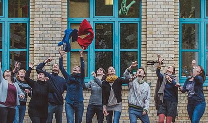 Eine Gruppe Menschen wirft Kleidung in die Luft