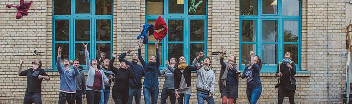Kinderkleidung mieten statt kaufen: Neue Geschäftsmodelle mit Sharing Economy Eine Gruppe Menschen wirft Kleidung in die Luft