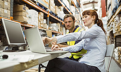 Mann und Frau arbeiten am Computer in einem Lagerhaus